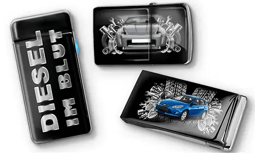 Drei schwarze Feuerzeuge mit Auto-Motiven und metallischen Akzenten. Eines trägt den Text „DIESEL IM BLUT“, die anderen zeigen rote und blaue Autos mit mechanischen Motiven. Ein sportlicher Ton wird vermittelt.