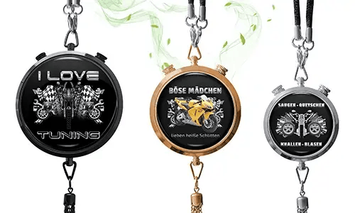 Three metallic pendants with chains: black with checkered flags, rose gold with yellow motorcycle, silver with engine graphic and bold German text
