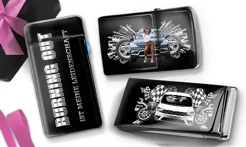 Drei schwarze Geldbörsen mit Auto-Designs. Eine trägt die Aufschrift „Burning Out ist meine Leidenschaft“, eine andere zeigt ein Auto mit Kolben und einer Person, und die dritte zeigt ein Auto mit karierten Flaggen und Kolben. In der Ecke liegt eine violette Schleife.