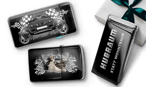 Three black wallets with car-themed designs and checkered flags, set against a white background. One shows a car with wheels, another features a couple, and one has 