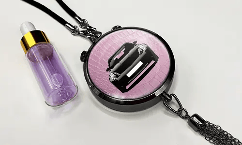 Pendant with pink background and white sports car, next to purple dropper bottle with gold cap