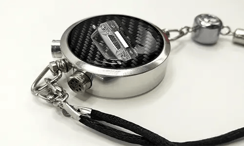 Round car key fob with carbon fiber face, buttons labeled LOCK and UNLOCK, braided black cord attached