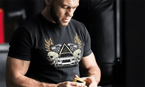 Schwarzes T-Shirt mit Grafik von Auto, Schädeln, Pistolen, goldenen Flügeln und sternförmigem Dreieckshintergrund