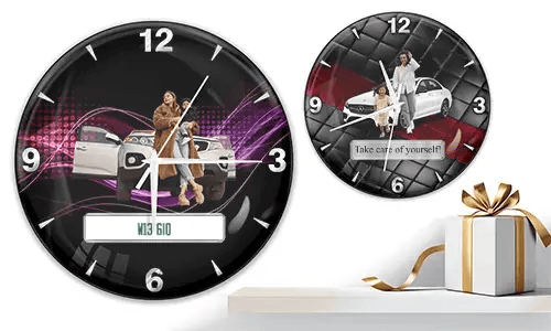 Two wall clocks with family car scenes: left with woman and child at white SUV over purple waves, right with white car and quilted red-black background