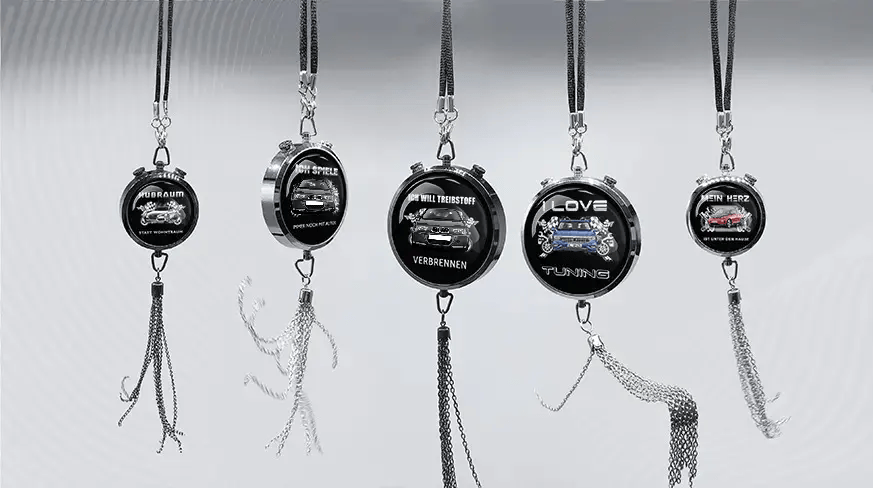Five round keychains with German car-themed slogans and illustrations, hanging in a row