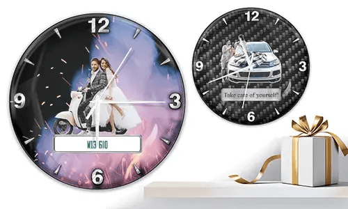 Zwei Wanduhren mit romantischen Fahrzeugmotiven: links mit Hochzeitspaar auf weißem Roller und Feuerwerk, rechts mit Paar und Auto auf Carbon-Hintergrund